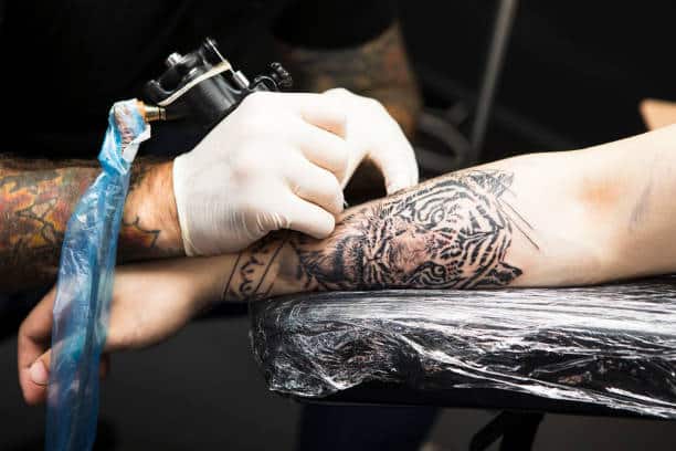 Artist making Tiger tattoo on arm