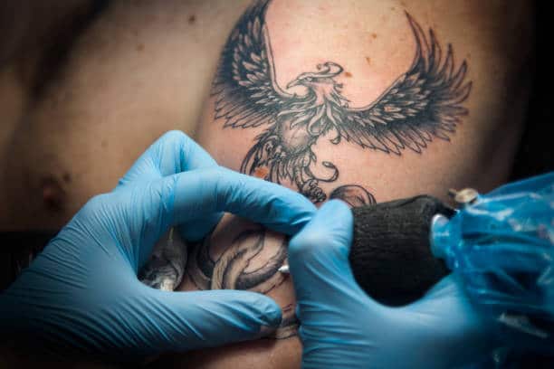 Artist making Phoenix Tattoo on arm