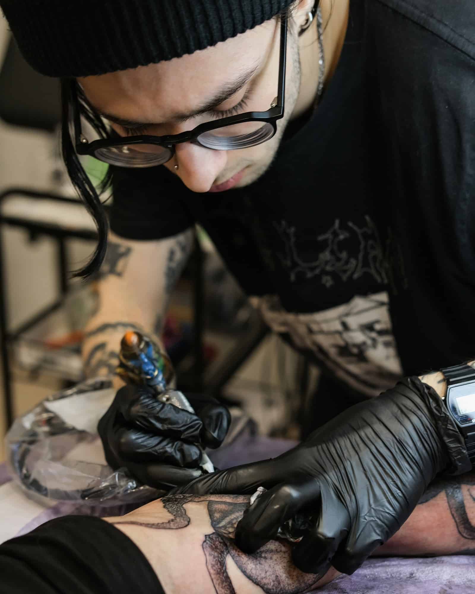 Professional tattoo artist stuffs a tattoo on the man's hand. Small business.