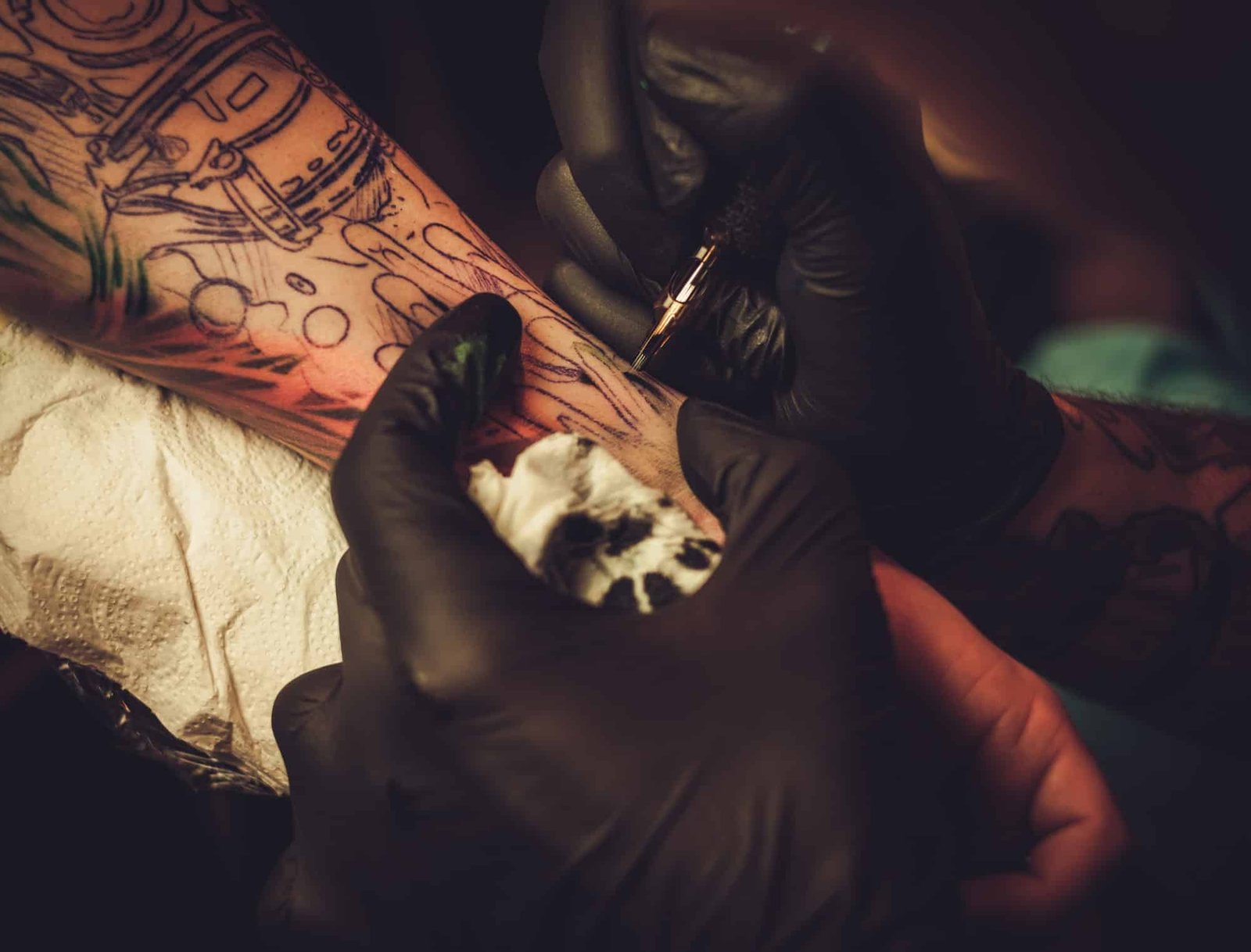 Tattoo artist makes a tattoo on a man's hand.