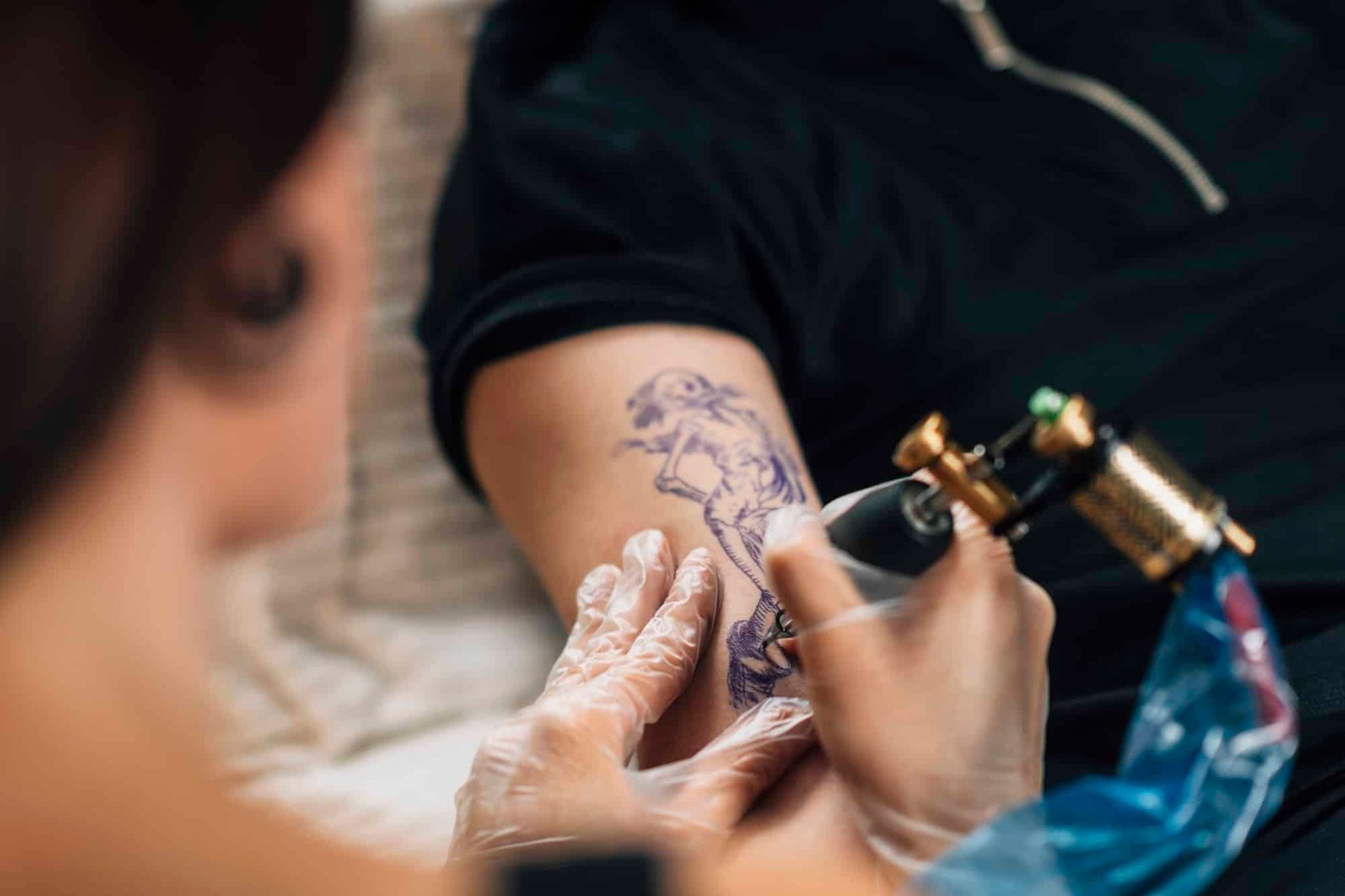 Tattoo Artist Tattooing Man’s Arm in Studio