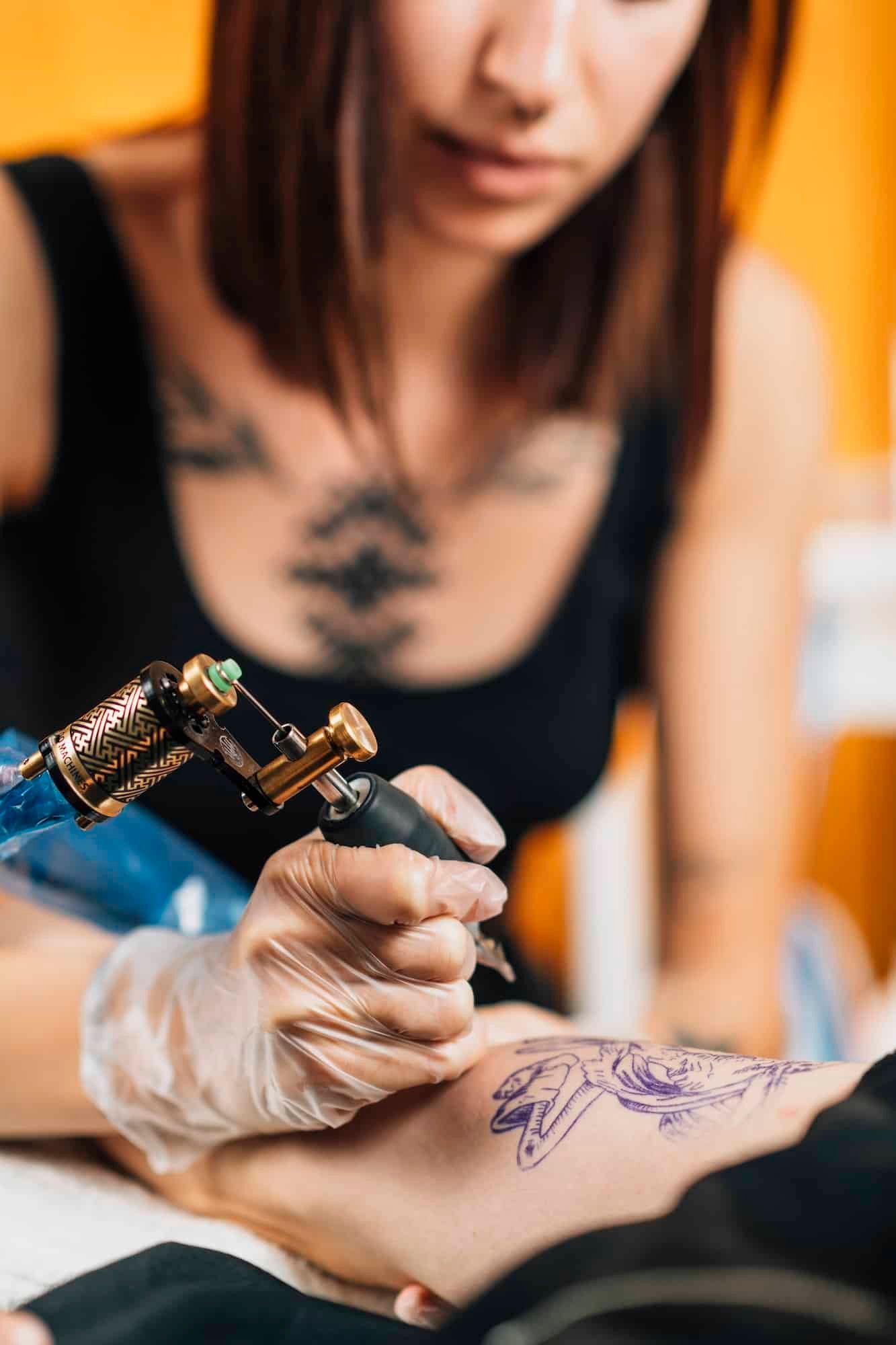 Tattoo Artist Tattooing Man’s Arm in Studio