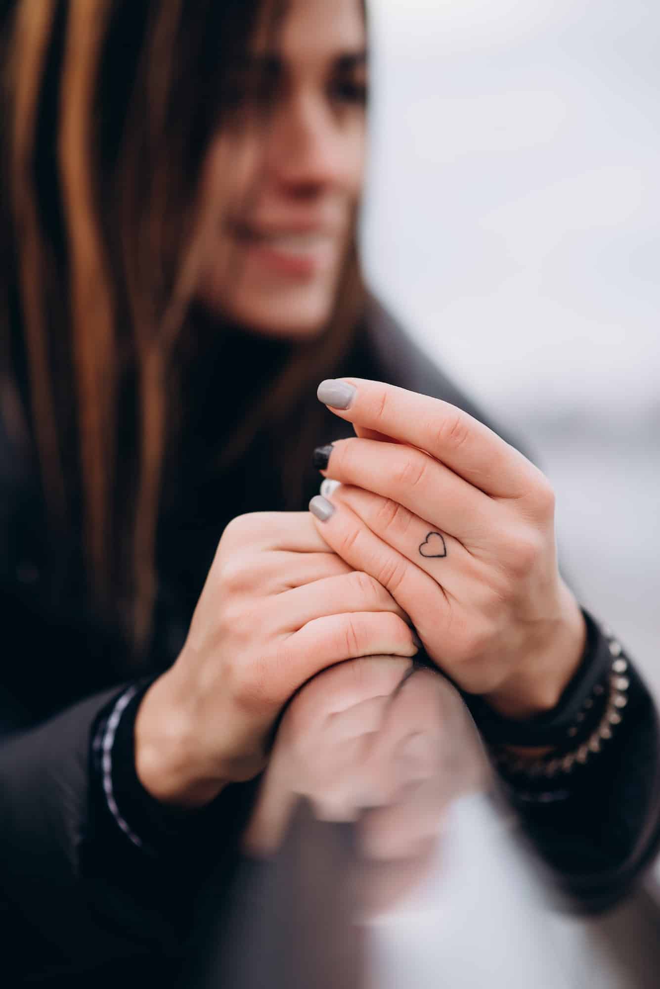 Tattoo in the form of a heart on the girl's finger.