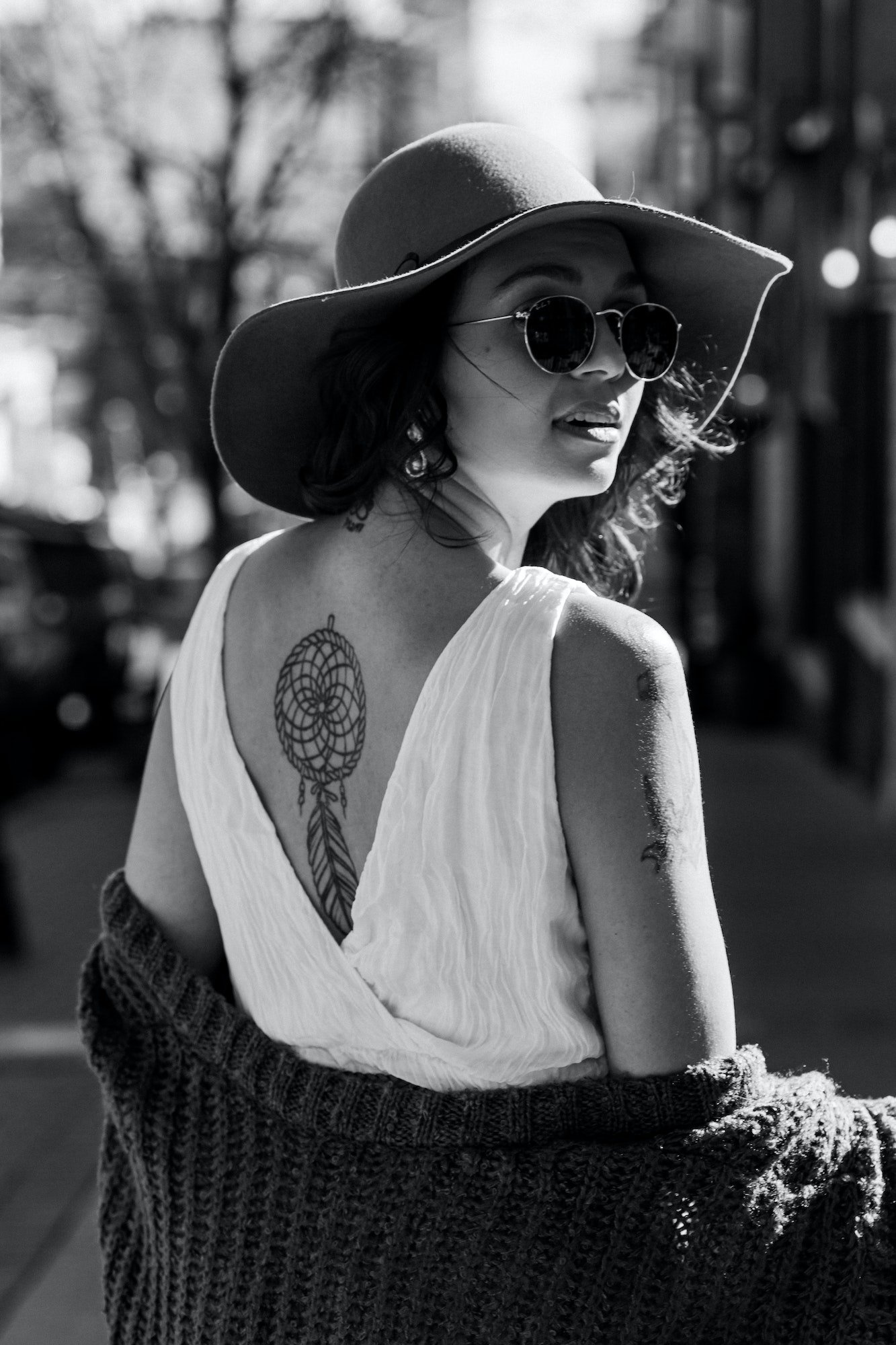 Beautiful woman in hat and white dress with the tattoo on the back