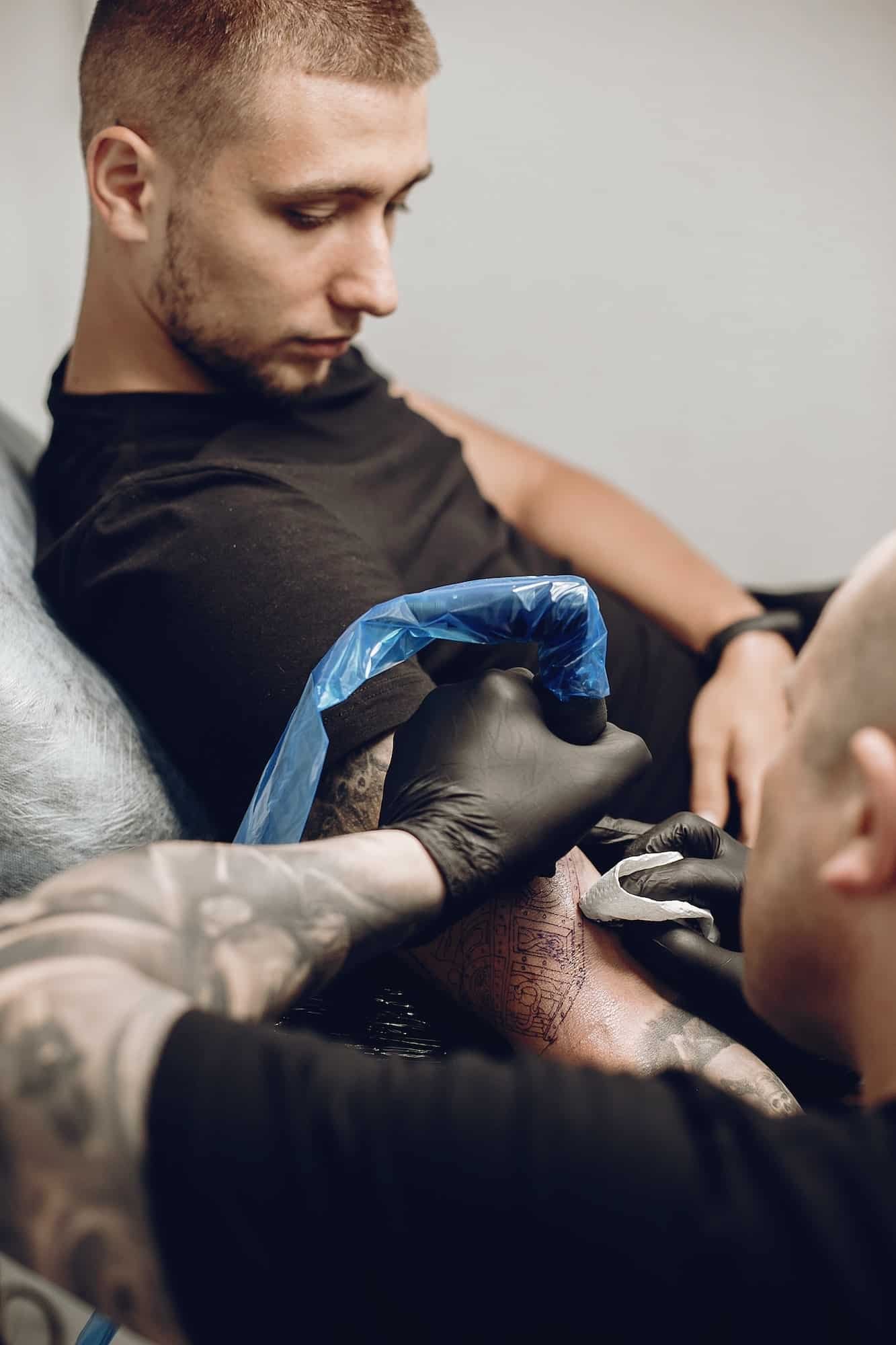 Man doing a tattoo in a tattoo salon, arm sleeve tattoos for men, full sleeve tattoo And Piercing