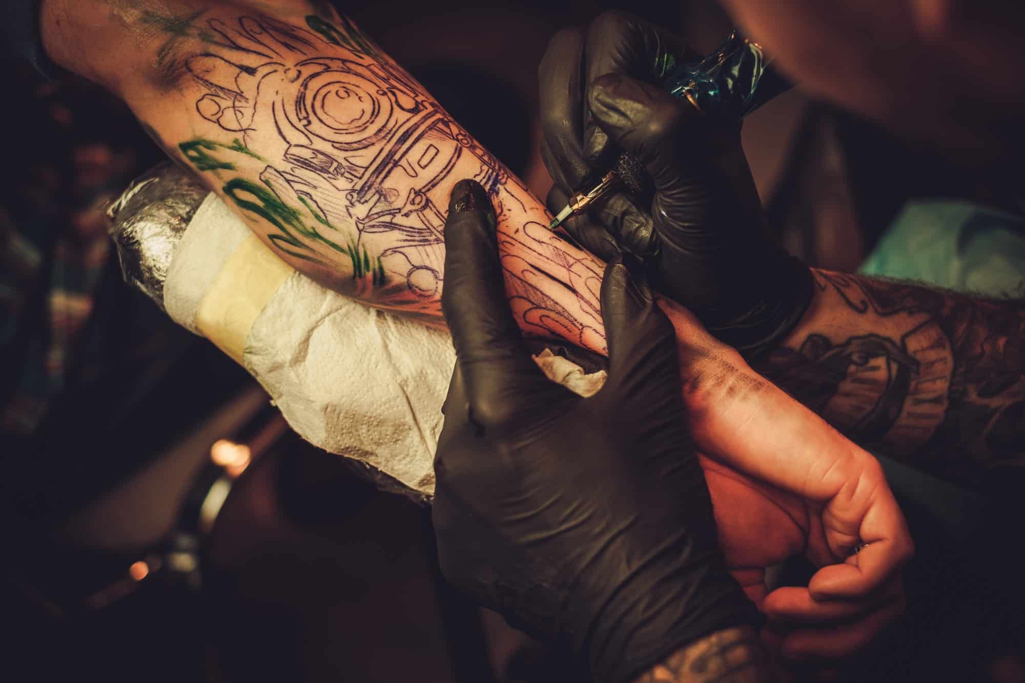 Tattoo artist makes a tattoo on a man's hand, Tattoo And Piercing Studio Forestdale