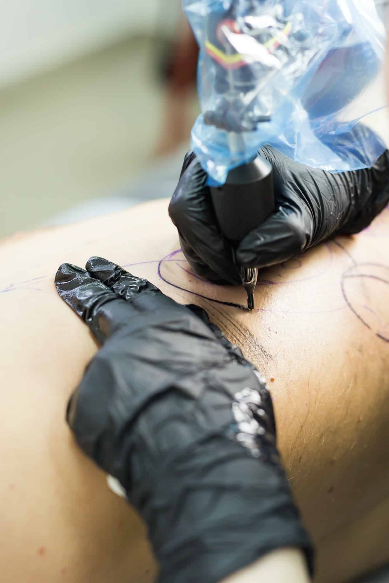 Close-up of a professional tattooer inking a Japanese sleeve tattoo on a woman,Small Back Tattoos for Men