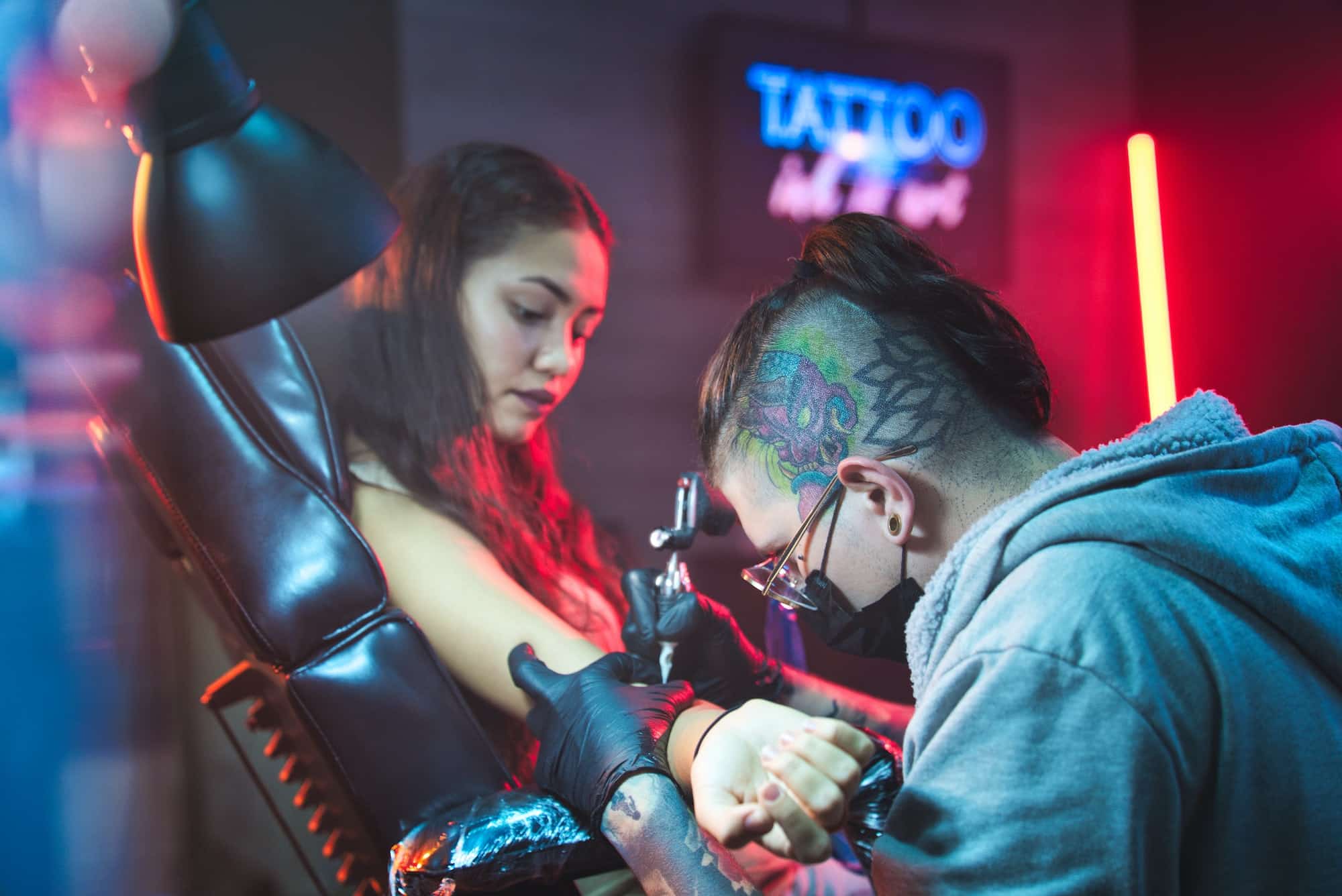 Artist Drawing Tattoo On Client In Parlor