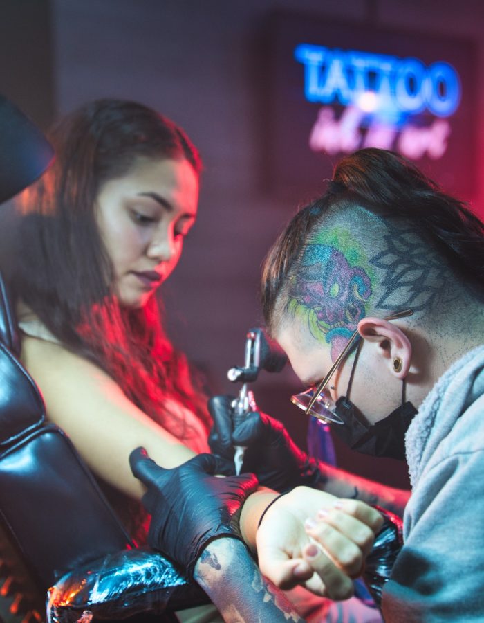 Artist Drawing Tattoo On Client In Parlor