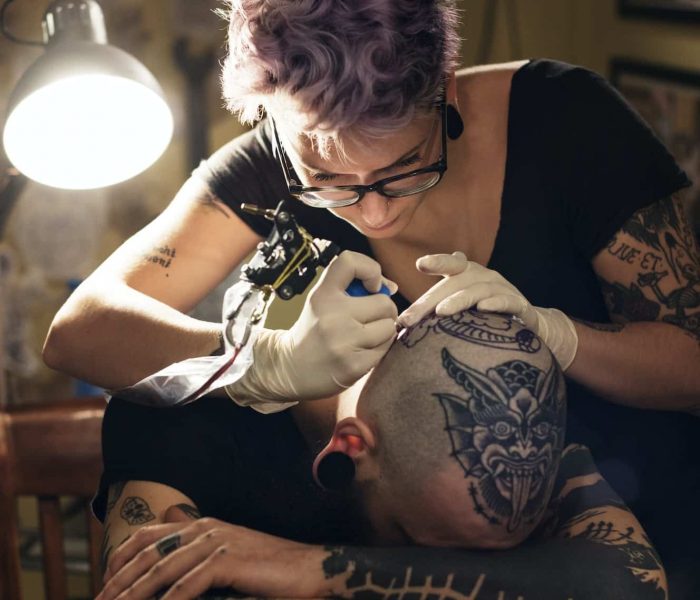 Female Tattoo Artist Tattooing Male Client In Studio