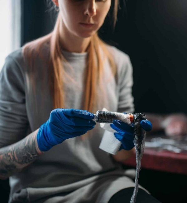 Female tattooist prepares tattoo machine