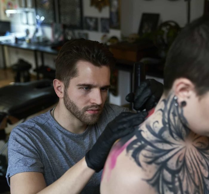 Focus caucasian man tattooing back of woman at the studio