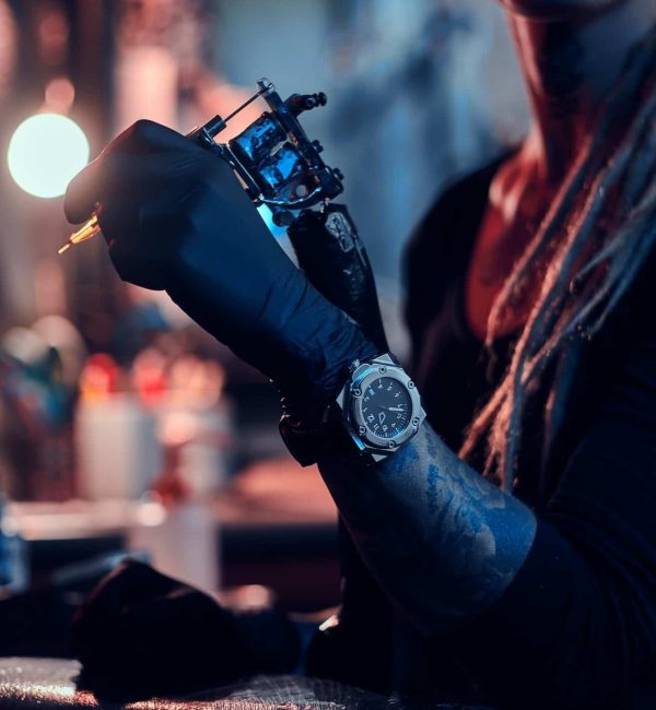 Hand of tattoo artist with tattooing machine in it