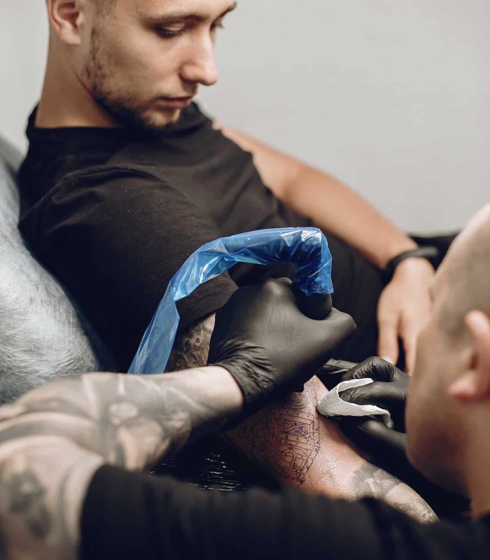 Man doing a tattoo in a tattoo salon, arm sleeve tattoos for men, full sleeve tattoo And Piercing