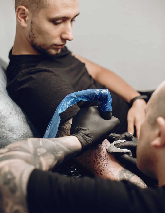 Man doing a tattoo in a tattoo salon, arm sleeve tattoos for men, full sleeve tattoo And Piercing