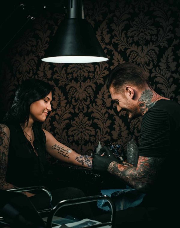 Professional tattoo artist makes a tattoo on a young girl's hand