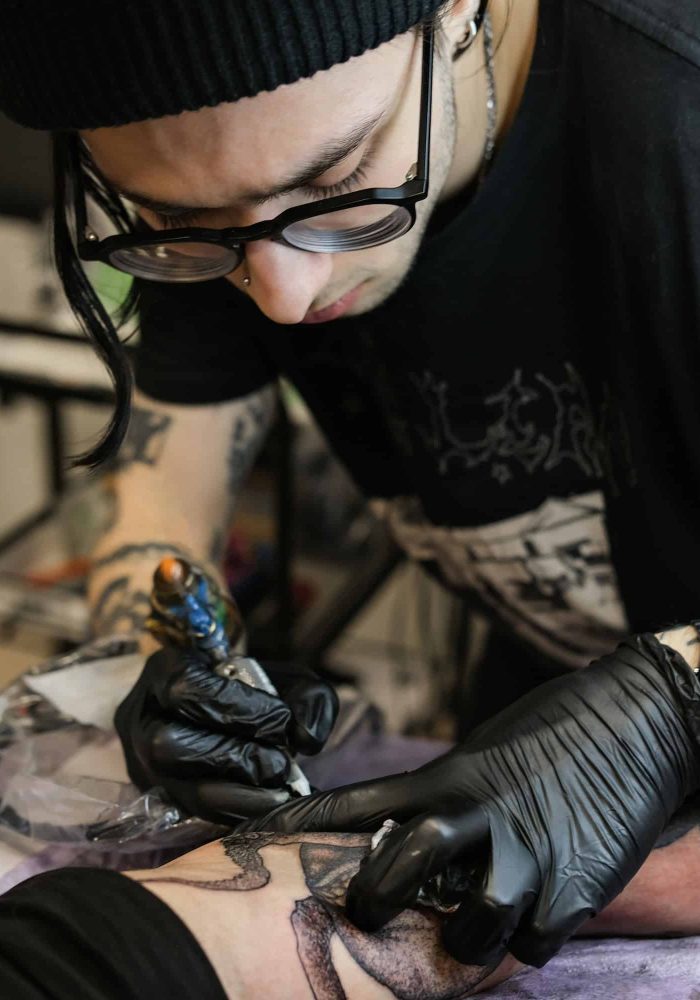 Professional tattoo artist stuffs a tattoo on the man's hand. Small business.