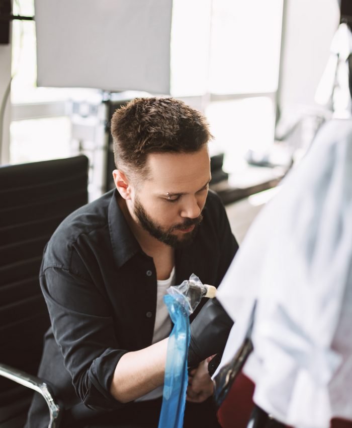 Professional tattoo master thoughtfully doing tattoo using tatto