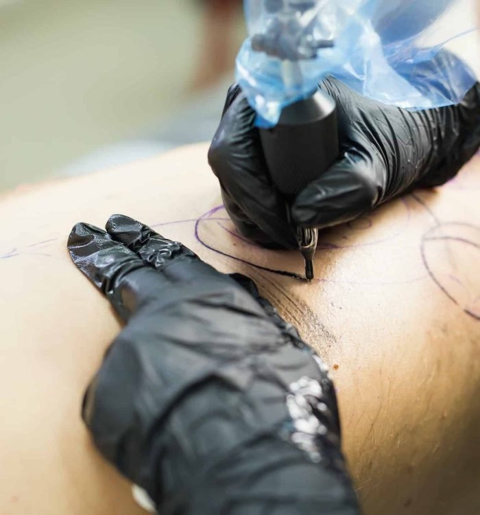 Close-up of a professional tattooer inking a Japanese sleeve tattoo on a woman