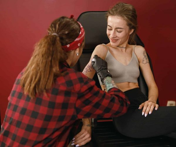 Tattoo artist carefully removing excess paint from the customer skin