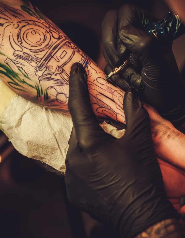 Tattoo artist makes a tattoo on a man's hand, Tattoo And Piercing Studio Forestdale