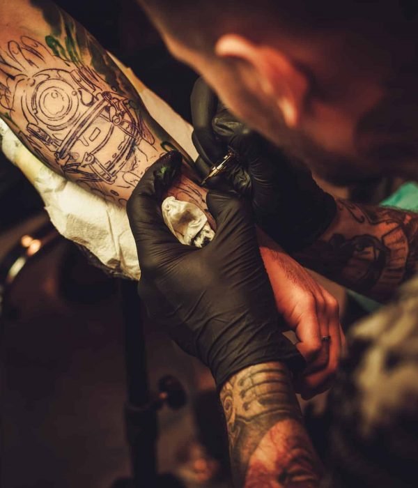 Tattoo artist makes a tattoo on a man's hand.