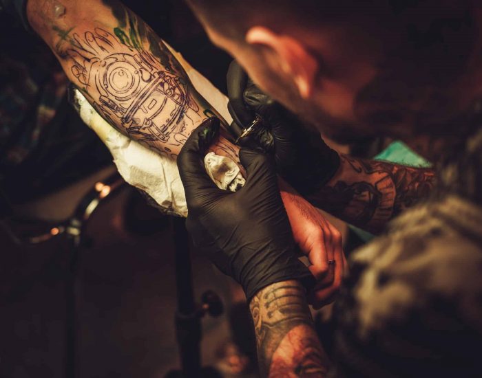 Tattoo artist makes a tattoo on a man's hand.