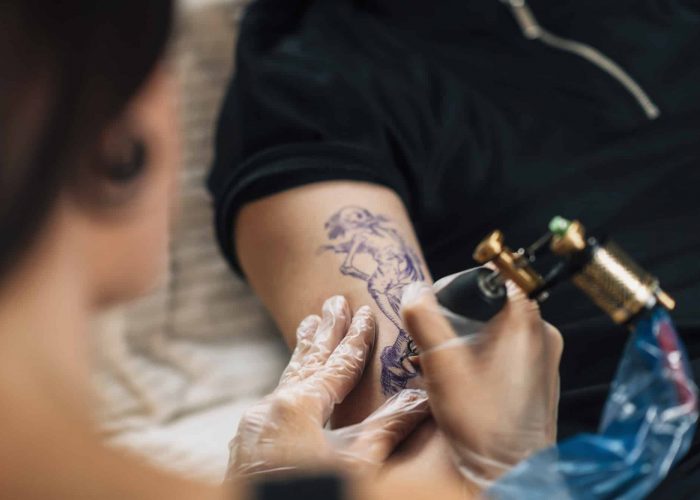 Tattoo Artist Tattooing Man’s Arm in Studio