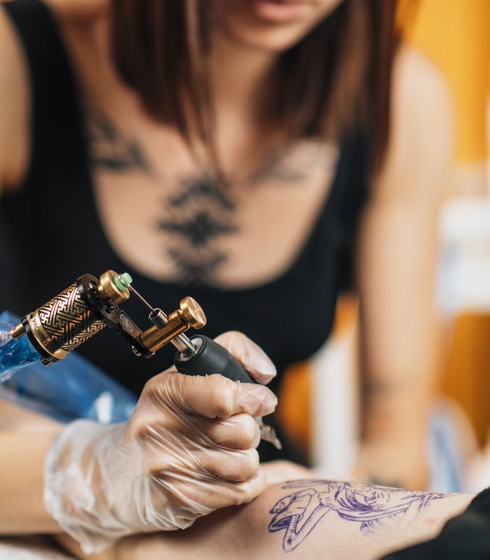 Tattoo Artist Tattooing Man’s Arm in Studio