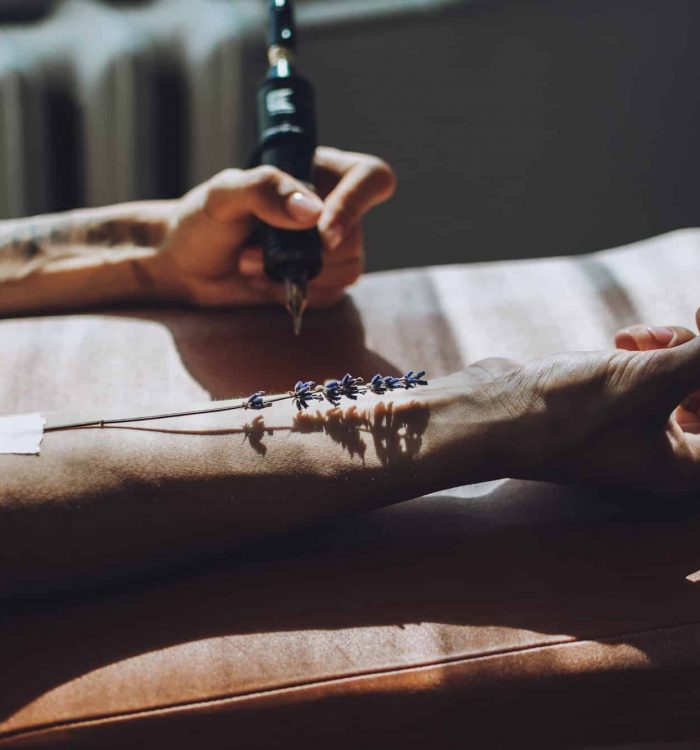 Tattoo design, creative artist working process. Close-up hand of tattoo master with tattoo machine