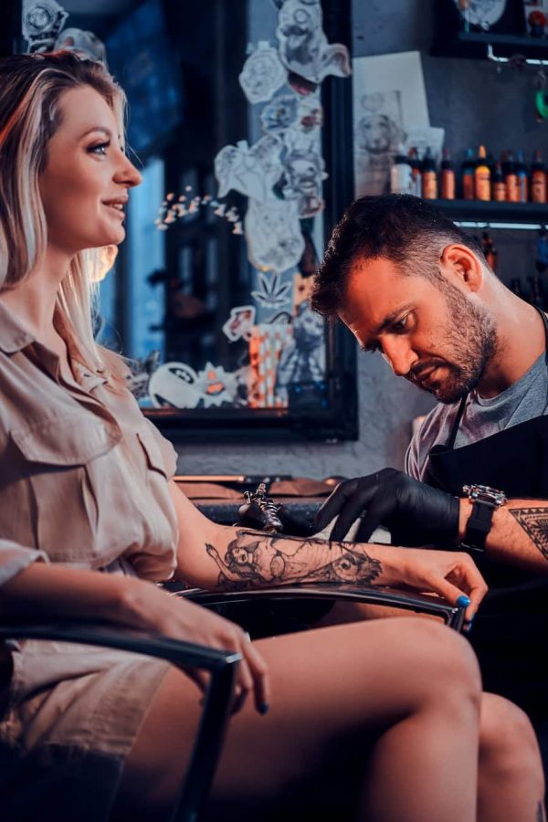 Tattoo master is creating new tattoo for customer