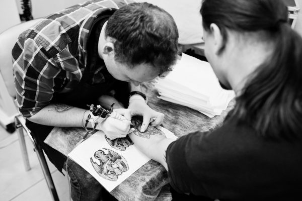Tattoo master make tattoo for rocker man at tattoo salon