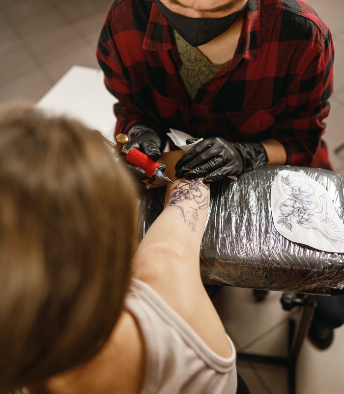 Vertical photo of tattoo artist inking tattoo on forearm