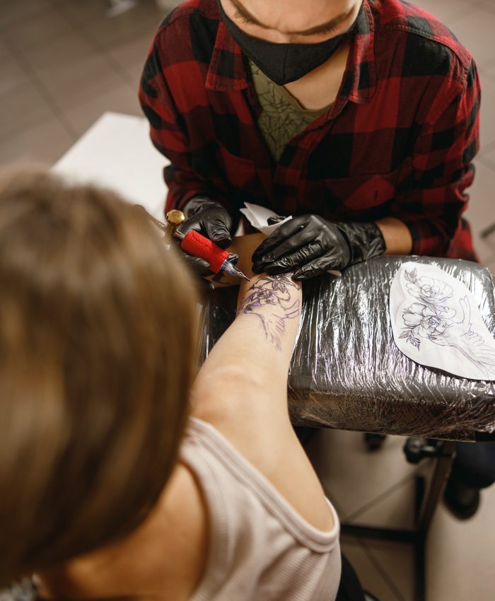 Vertical photo of tattoo artist inking tattoo on forearm